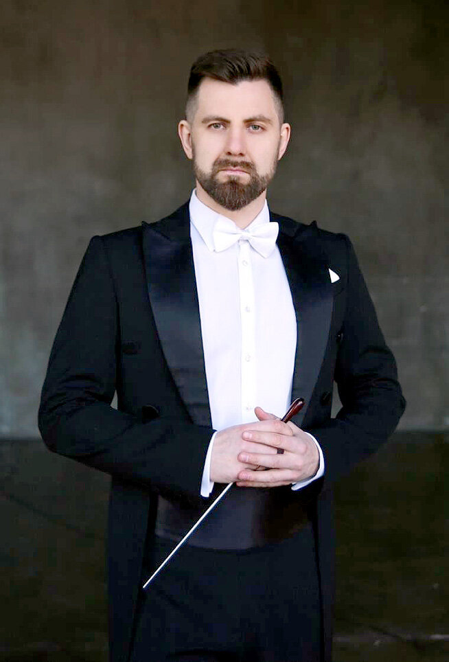 Conductor Vladimir Yatskevich in tailcoat with baton